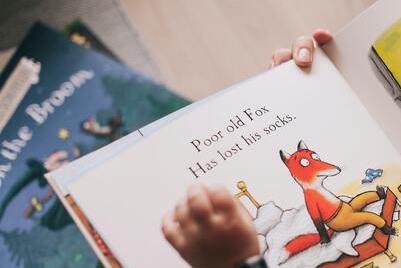 child and adult reading picture book
