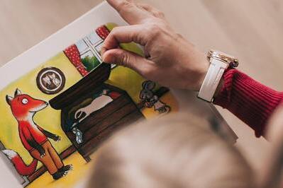 child and adult reading picture book