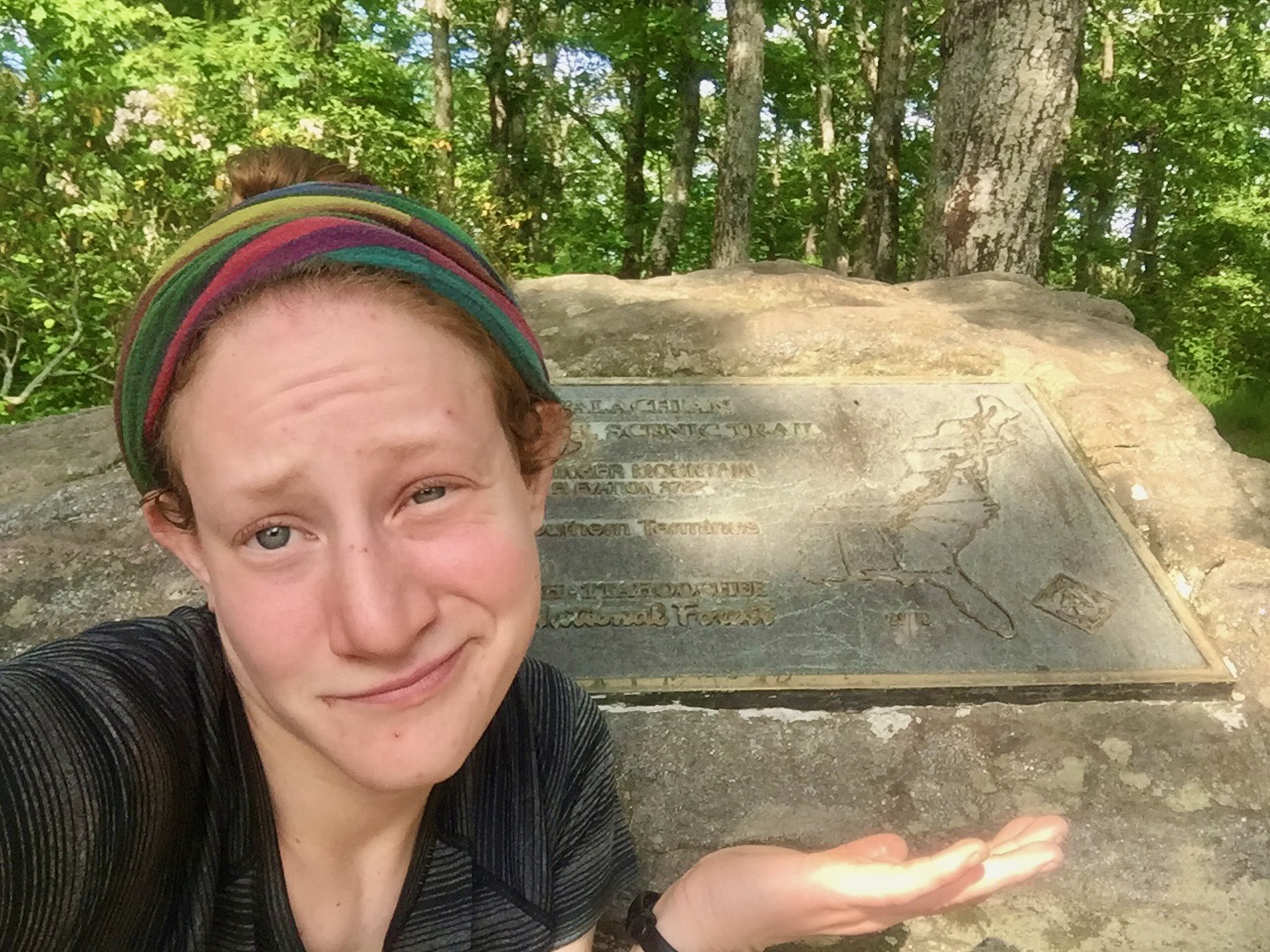 Selfie of me shrugging in front of the small metal plaque marking the southern terminus